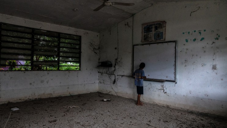 A young boy stands inside of what was his classroom in the community of Constitucion de 1917. The elementary school has had to be abandoned since it is partially destroyed by floods, erosion and the rising water levels in the river. The school’s sports fields are now completely flooded. Date: 2021.09.10. Photo: César Rodríguez/Norwegian Red Cross.